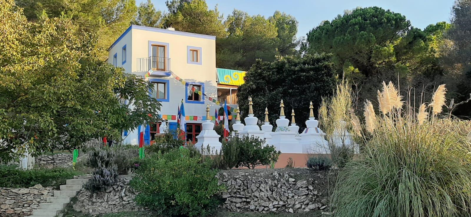 El centro Bokar Thubten Ling entre pinos de Ibiza, con las estupas blancas y banderas de oracion frente a la casa