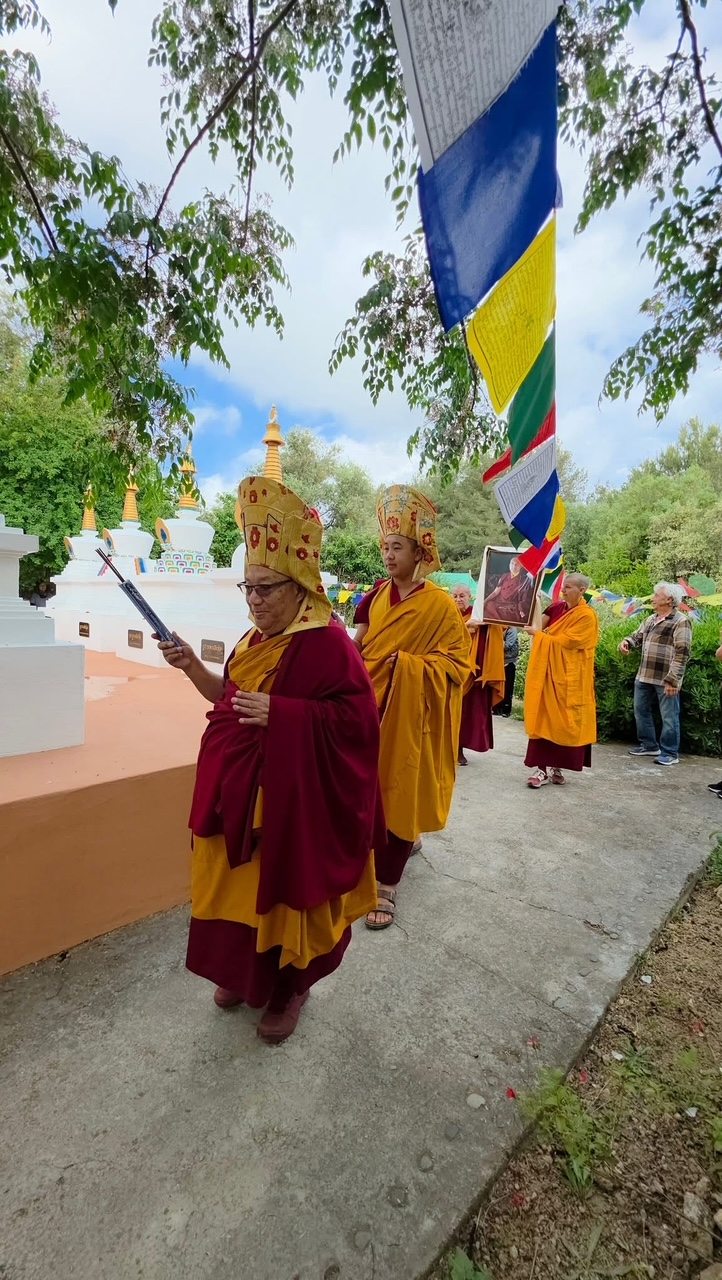 Procesión de maestros portando un retrato del linaje, junto a las estupas del centro
